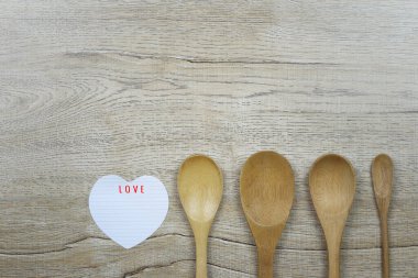 Kağıt kalp şekli ve tahta kaşık ahşap zemine yerleştirilmiş ve Aşk ve Sevgililer Günü konseptinde tasarım için bir kopya alanı var..