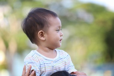 Asyalı çocuk annesinin boynuna biniyor. Annesinin çocuklara olan sevgisi..