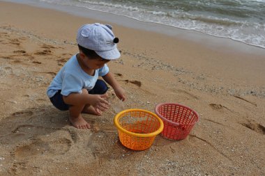 Asyalı çocuklar açık havada kumsalda oynuyorlar..