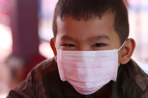 Asian boy wearing a white mask for preventing germs from entering the body through the nose and mouth,Concept of preventing the common cold and corona virus.