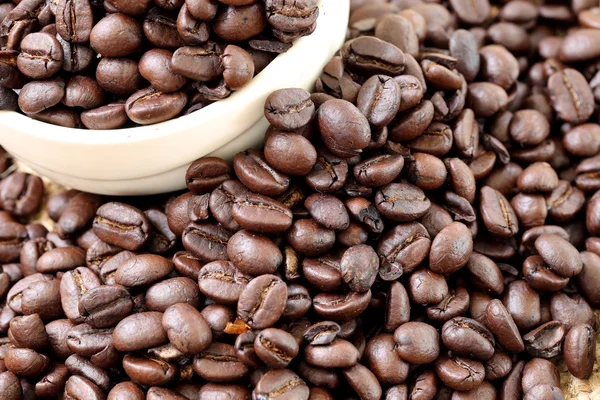 Coffee beans placed on bag sack and white cup. — Stock Photo, Image