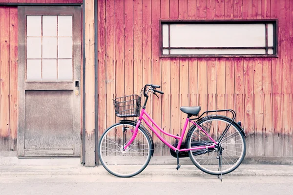 Bicicleta rosa y viejas paredes de madera . — Foto de Stock