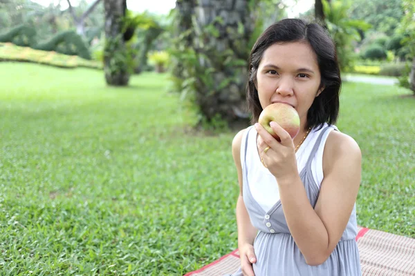 Thai schwangere Mutter zu essen Apfel im Garten. — Stockfoto