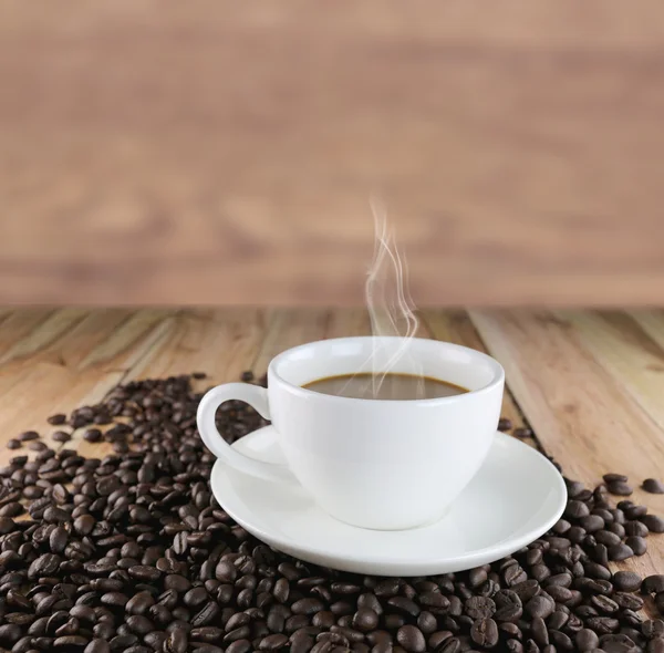 Taza de café blanco y granos de café tostados . — Foto de Stock