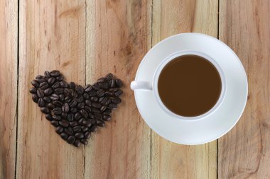 Beyaz kahve fincanı ve kahve çekirdeği kalp şekli olan.