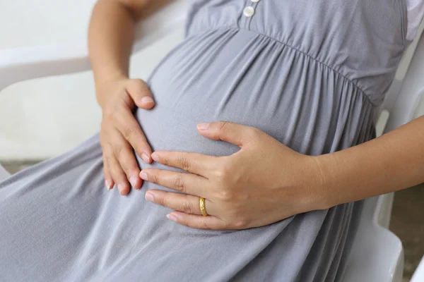 Mulheres grávidas colocaram a mão em sua barriga . — Fotografia de Stock