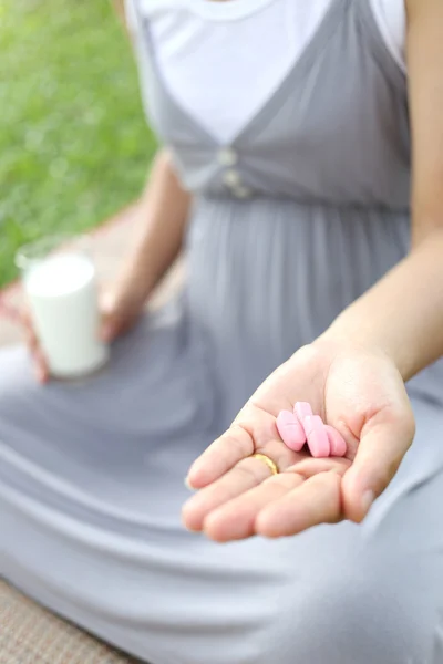 孕妇喝一杯牛奶和维生素丸在手到 — 图库照片