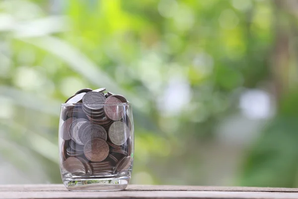 Zilveren munt in glas wordt geplaatst op een houten vloer met kleurrijke bok — Stockfoto