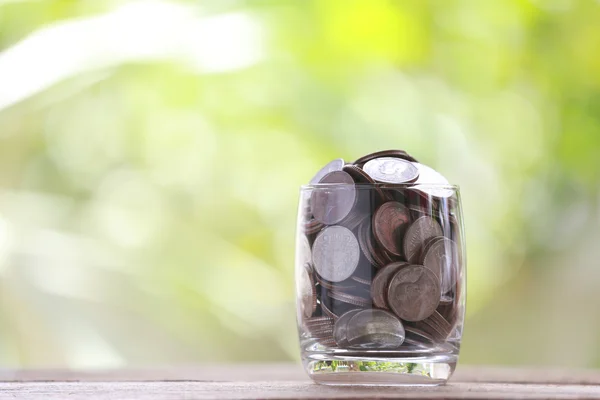 Ασημένιο νόμισμα σε ποτήρι τοποθετείται σε ένα ξύλινο πάτωμα με πολύχρωμο bok — Φωτογραφία Αρχείου