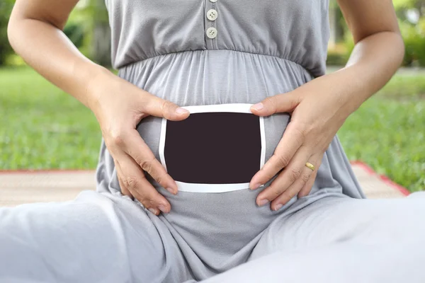 Pregnant women show ultrasound film picture on her belly.