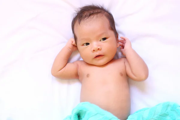 Neugeborenes Baby aus Asien entspannt gut gelaunt auf weißem Bett. — Stockfoto