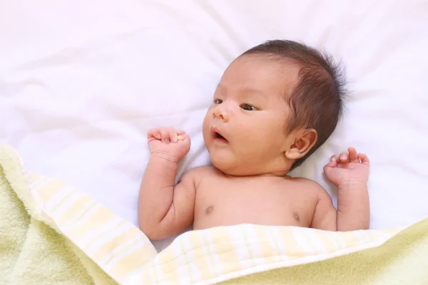 Νεογέννητο μωρό της Ασίας να χαλαρώσετε σε μια καλή διάθεση σε λευκό κρεβάτι. — Φωτογραφία Αρχείου