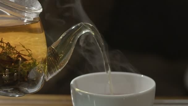 З прозорого скляного чайника наливаємо чорний чай в дві чашки — стокове відео