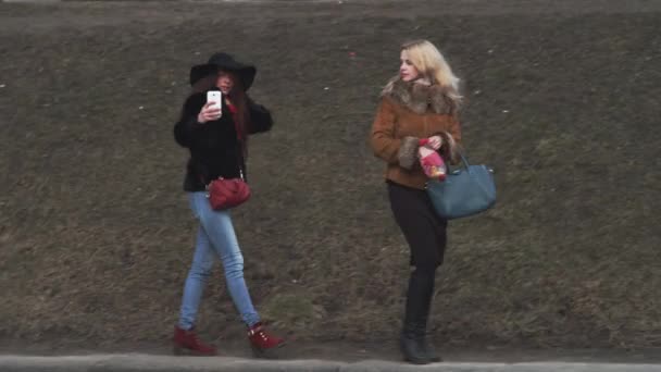İki güzel kadınlar buzlu nehir enbankment üzerinde yürüme ve güvercin besleme — Stok video