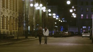 İki genç güzel kadın yürüyüş ve gece şehrin bir sokak konuşuyor
