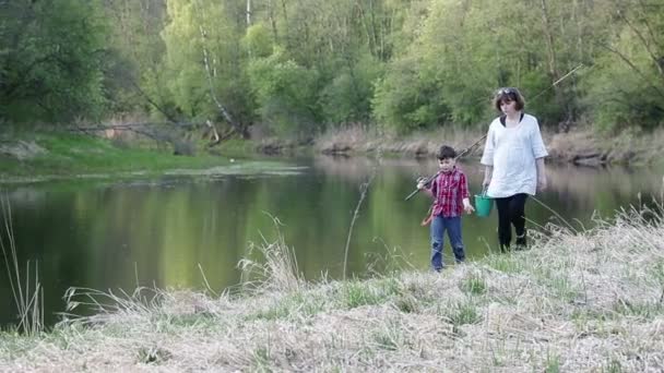 Leuke zwangere vrouw met haar zes jaar oude zoon gaan vissen op de oevers van de rivier — Stockvideo