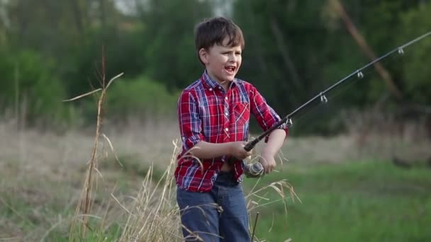 Un niño de seis años atrapa un pez. su mamá lo besa — Vídeo de stock