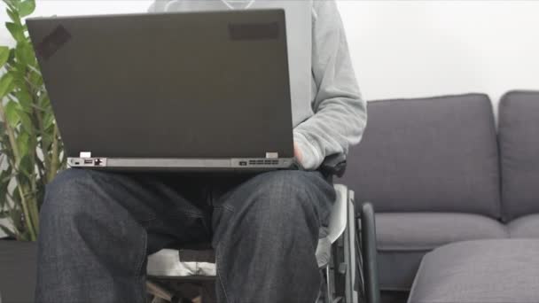 Joven en silla de ruedas con portátil — Vídeos de Stock