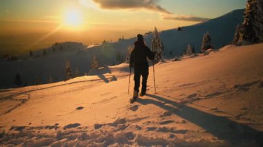 Gün batımında karlı mointain 'de yürüyüş yapan kadın.
