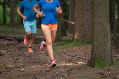 Orman ağaçlarının arasında koşan çift