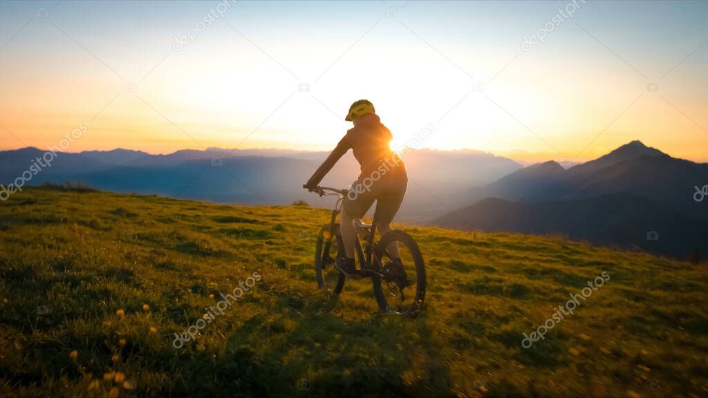 Woman riding mountain bike into the sunset