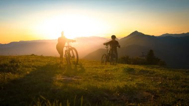 Motosikletleri çimenli tepenin üzerinden itmek