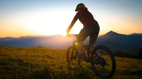 Mulher montando bicicleta de montanha para o pôr do sol — Fotografia de Stock