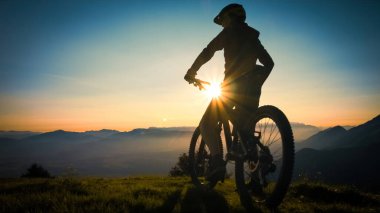 Bisikletçi silueti gün batımını izliyor