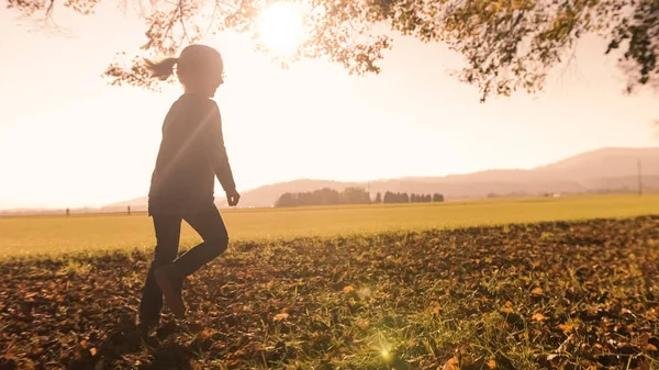 Niña preescolar corriendo sobre hojas secas —  Fotos de Stock