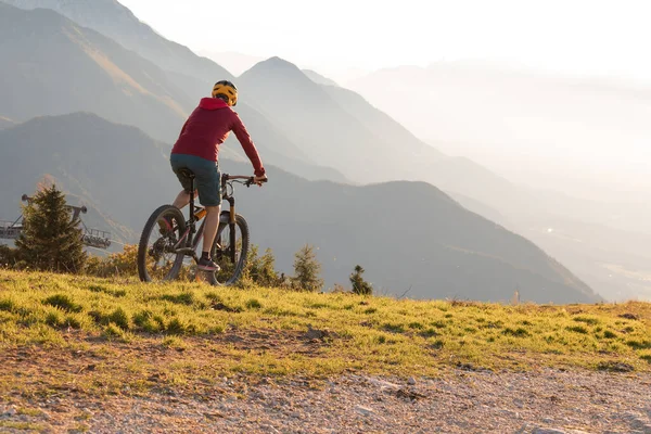 Mulher montando bicicleta de montanha para o pôr do sol — Fotografia de Stock