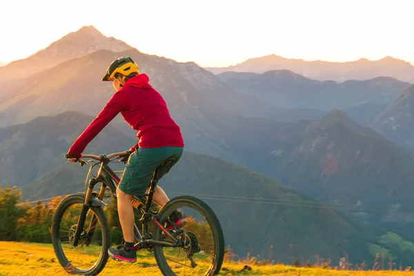 Mujer montando bicicleta de montaña en el atardecer — Foto de Stock