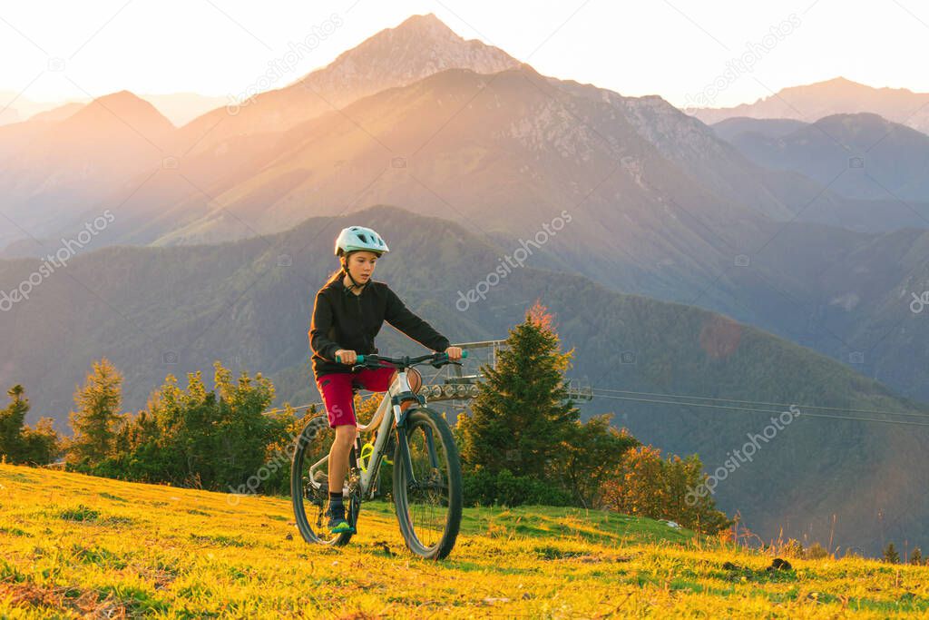 Girl child riding mountain bike into the sunset