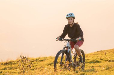 Dağ bisikletine binen kız gün batımına doğru