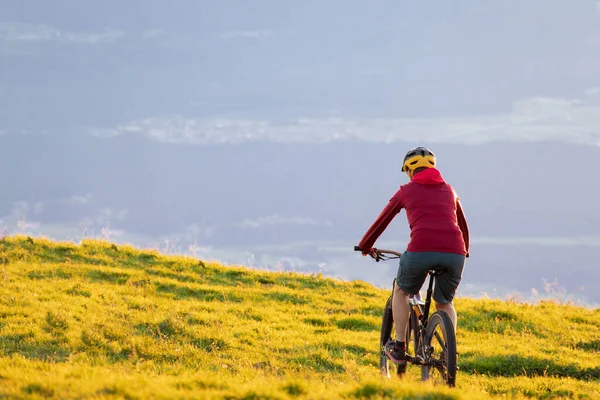 Mulher montando bicicleta de montanha para o pôr do sol — Fotografia de Stock