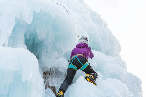Mulher escalando uma encosta gelada — Fotografia de Stock