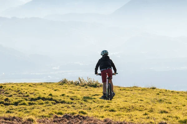 日落时骑山地自行车的女孩 — 图库照片