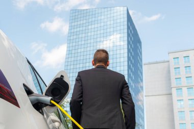 İşadamı elektrikli arabayı şarj ediyor.