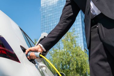 İşadamı elektrikli arabayı şarj ediyor.