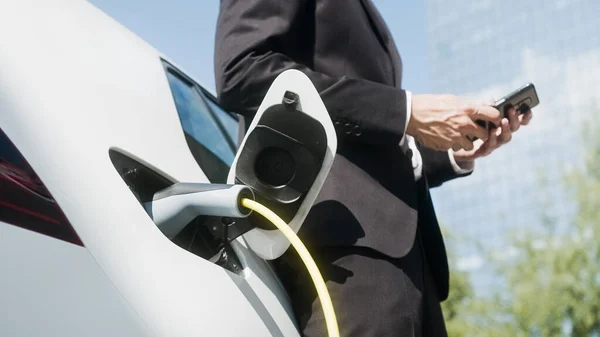 Empresario en una estación de carga de vehículos eléctricos — Foto de Stock