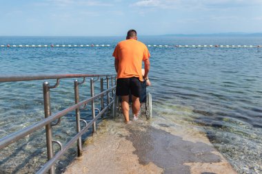 Tekerlekli sandalyedeki adam rampadan denize