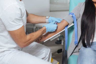 Profesyonel flebotomist, genç ve güzel Asyalı bir kadının kolundaki damardan kan örneği alıyor. Kan çekme konsepti.