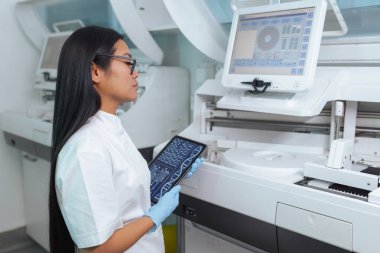 Teknisyen, çalışma vardiyası sırasında modern bir laboratuvar ortamında dijital laboratuvar verilerini bir ekranda inceliyor..