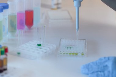 Laboratuar bilimcisi, biyoloji, kimya veya tıptaki sıvı hacmini ölçmek için hassas dijital pipet kullanıyor. Tüpler için sıvı damlatıyor..