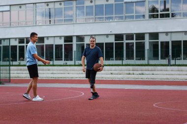 Protez bacaklı bir adam, akşam saatlerinde bir arkadaşıyla sahada basketbol oynamaktan hoşlanır..