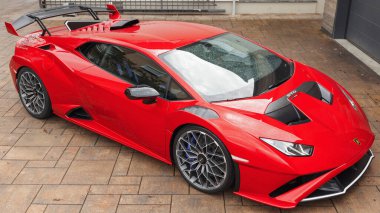 Slovenya, Ljubljana - 9 Ekim 2025: Kırmızı Lamborghini Huracan STO yağmurlu bir şehir caddesine park etmiş, tasarımını sergiliyor.