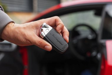 Slovenya, Ljubljana - 9 Ekim 2025: Lamborghini Huracan STO anahtarı kırmızı bir spor arabanın yanında bir bayi tarafından tutuluyor.