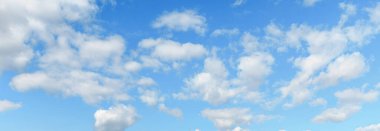 Güneşli bir günde, parlak mavi gökyüzünde huzur içinde süzülen beyaz bulutlar sakin bir atmosfer yaratıyor..