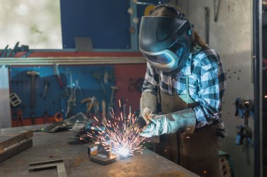 Kadın kaynakçı aile işlerinde MIG kaynak işlemini başarıyla gerçekleştiriyor. Sanatçı kadın, ilham ve kişisel gelişim kavramları.