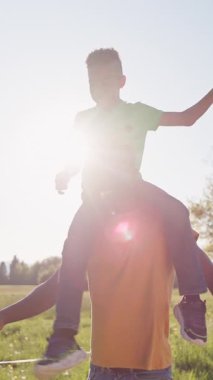 Neşeli bir baba oğlunu omuzlarında taşır, kollarını açar gibi açar, doğada eğlenir gibi eğlenir.