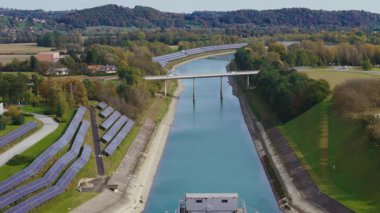 Nehir boyunca yeşil bir enerji tesisinin yakınına kurulmuş güneş panelleri yenilenebilir enerjiyi iş başında gösteriyor..